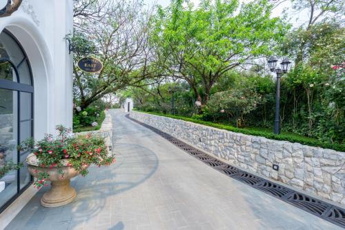 a walkway next to a stone wall with flowers in a vase at Silk Path Grand Sapa Resort & Spa in Sa Pa