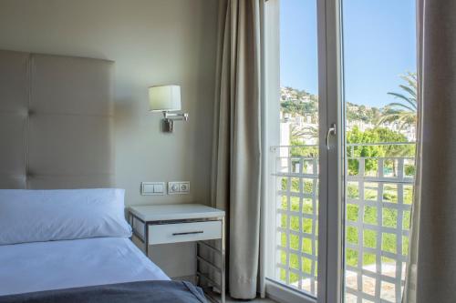 a bedroom with a bed and a view of a balcony at Hotel Atlántico in Zahara de los Atunes