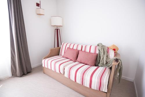 a striped couch in a room with a lamp at Zenitude Hôtel-Résidences Narbonne Centre in Narbonne