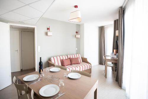 sala de estar con mesa y sofá en Zenitude Hôtel-Résidences Narbonne Centre en Narbona