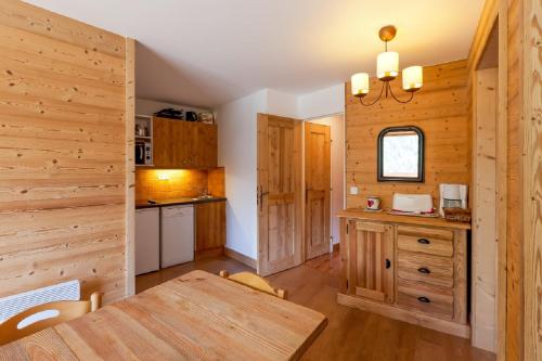 a kitchen with wooden walls and a wooden table at Residence Les Sentiers du Tueda - maeva Home in Méribel