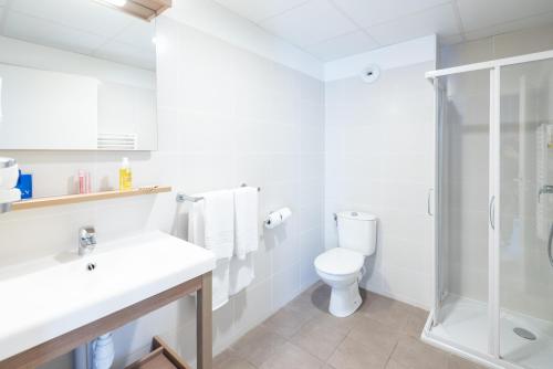 a white bathroom with a toilet and a shower at Zenitude Hôtel-Résidences Narbonne Centre in Narbonne