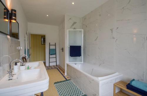 La salle de bains blanche est pourvue d'une baignoire et d'un lavabo. dans l'établissement Château de Cadouzan, à Saint-Dolay