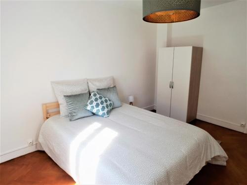 a bedroom with a white bed with blue pillows at Au 36, Les Apparts Hotel Joigny in Joigny