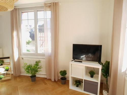 a living room with a flat screen tv on a white cabinet at Au 36, Les Apparts Hotel Joigny in Joigny
