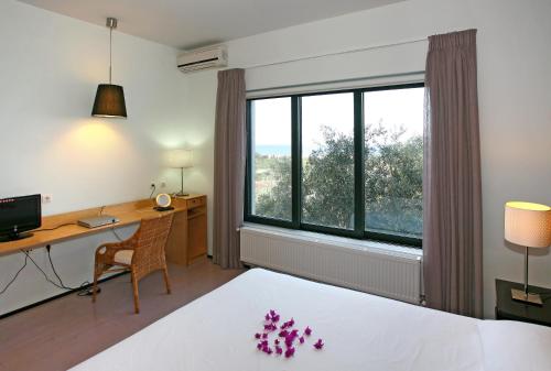 Habitación de hotel con cama, escritorio y ventana en Villa Bamboo, en Máleme