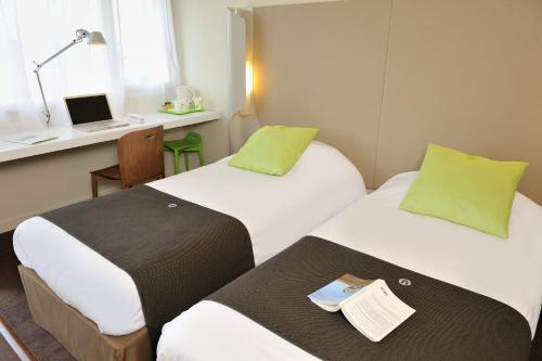 Cette chambre comprend deux lits et un bureau avec un ordinateur portable. dans l'établissement Campanile Vannes, à Vannes