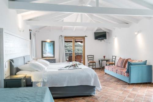 a bedroom with a bed and a couch and a tv at Enetiko Resort in Parga