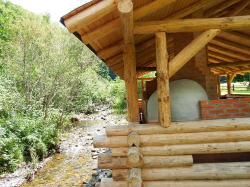 a building with a wooden roof next to a creek at Casa din Vale in Săcuieu