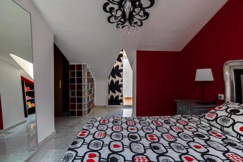 1 dormitorio con cama y pared roja en La Buhardilla de Olivia, en Málaga