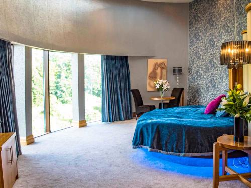 a bedroom with a blue bed and a large window at The Riverside Park Hotel in Enniscorthy