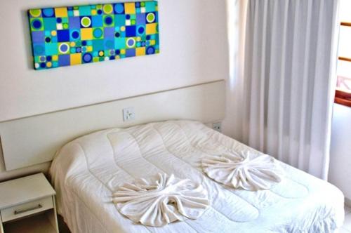 1 cama blanca en un dormitorio con una pintura en la pared en Resid. Moradas de Israel - Tonziro, en Porto Seguro