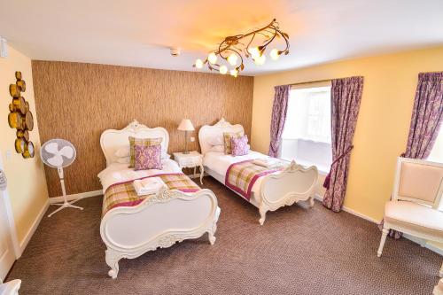 a bedroom with two beds and a chair at The George Hotel in Axminster