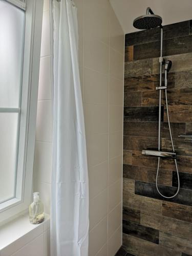 a shower with a white shower curtain next to a wooden wall at studio B&B Zeeuws licht in Westkapelle