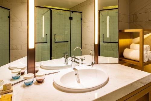 a bathroom with two sinks and a large mirror at Metropolo Jinjiang Weihai Railway Station in Weihai