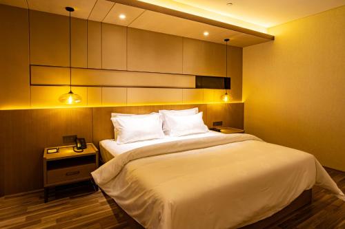 a bedroom with a large bed with white sheets and pillows at Metropolo Jinjiang Weihai Railway Station in Weihai