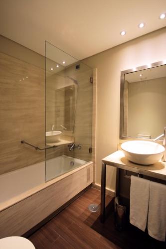 a bathroom with a sink and a tub and a mirror at Hotel Lux Fatima in Fátima