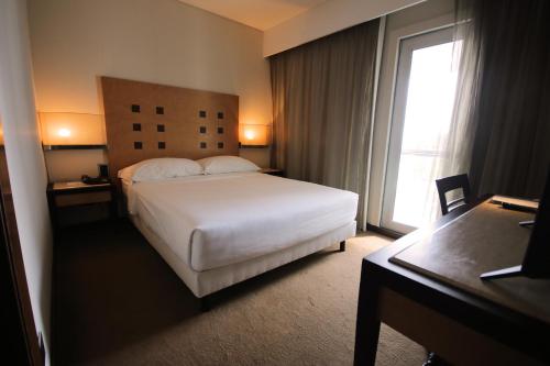 a hotel room with a white bed and a window at Hotel Lux Fatima in Fátima