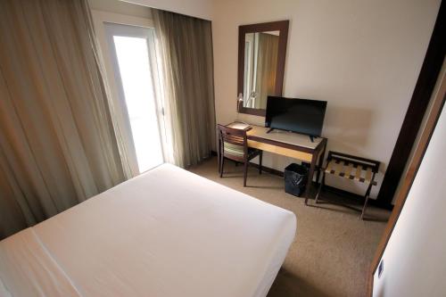 a bedroom with a bed and a desk with a television at Hotel Lux Fatima in Fátima