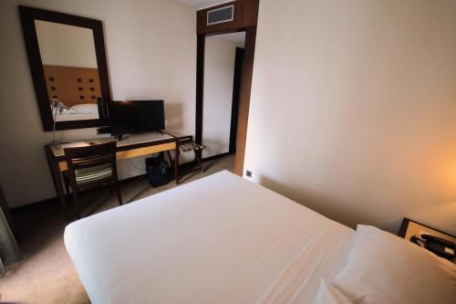 a bedroom with a bed and a desk with a mirror at Hotel Lux Fatima in Fátima