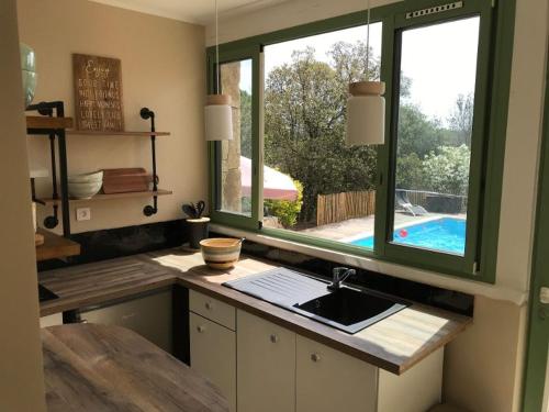 a kitchen with a sink and a window and a pool at Maison Ferruccio in Porto-Vecchio