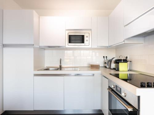 une cuisine blanche avec un évier et un micro-ondes dans l'établissement Apartment Résidence Cita di Sali-7 by Interhome, à Porto-Vecchio