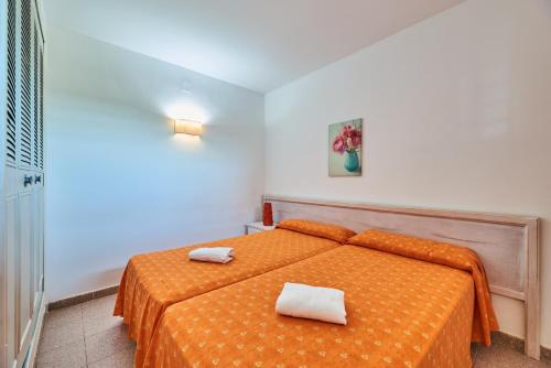 a bedroom with a orange bed with two towels on it at Inter Apartments in Salou