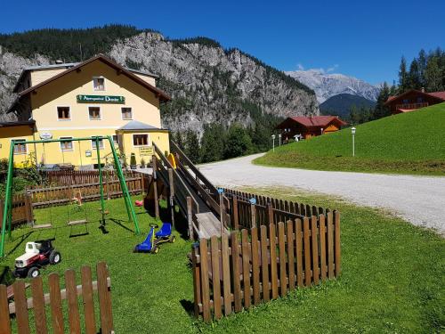 a playground in front of a house with a fence at Alpengasthof Draxler in Forstau