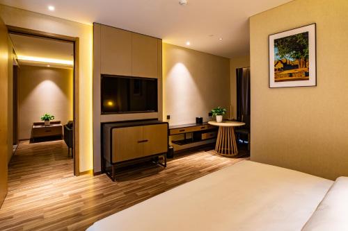 a hotel room with a bed and a flat screen tv at Metropolo Jinjiang Weihai Railway Station in Weihai