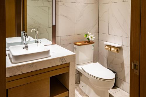 a bathroom with a white toilet and a sink at Metropolo Jinjiang Weihai Railway Station in Weihai