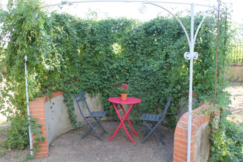 a red table and two chairs in front of a hedge at CLOS MARIE in Iguerande