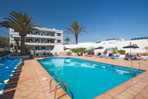 a large swimming pool with palm trees and a hotel at Costa Luz Beach Apartments in Puerto del Carmen