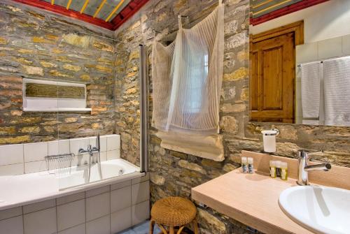 a stone bathroom with a tub and a sink at Anovolios Boutique Hotel in Agios Georgios Nilias