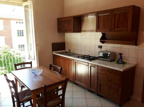 a kitchen with wooden cabinets and a table with a microwave at ASTI centro, appartamento MANUELA in Asti