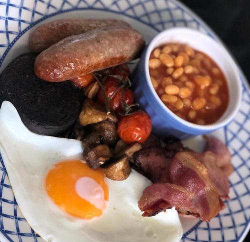 un piatto di cibo con uova, pancetta, fagioli e una salsiccia di The Bosk @ Breamish Valley Cottages a Ingram