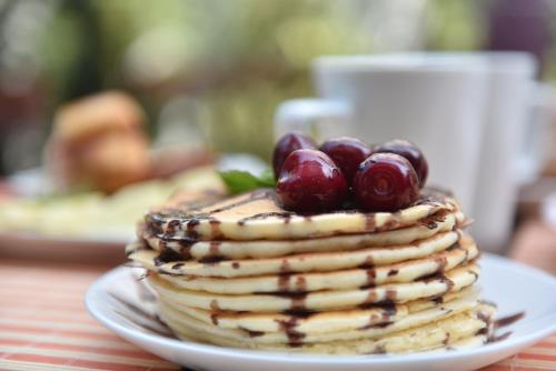 a stack of pancakes with cherries on a plate at Prior Hotel in Prizren
