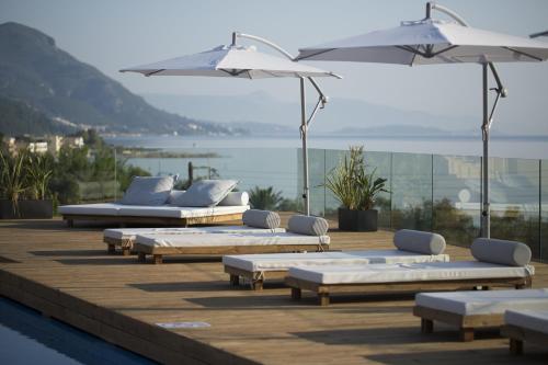 a row of chaise lounges and umbrellas on a deck at Ionian Eye Design Studios & Spa in Mesongi