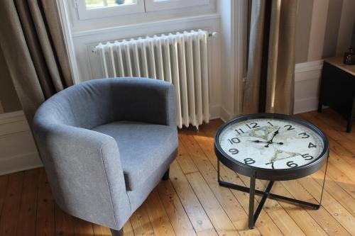 a chair and a table with a clock in a room at CLOS MARIE in Iguerande