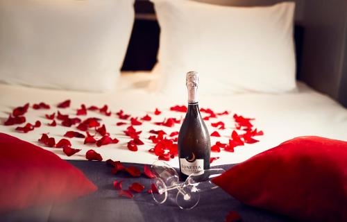 - une bouteille de champagne sur un lit avec des fleurs rouges dans l'établissement WestCord Art Hotel Amsterdam 4 stars, à Amsterdam