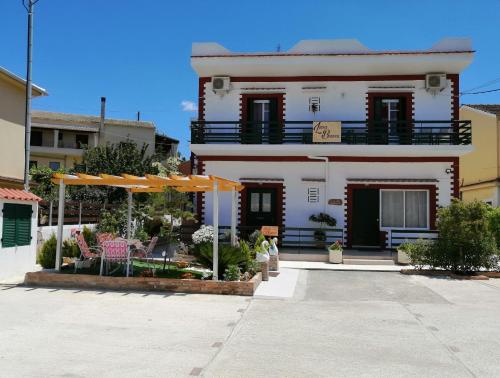 a white house with an umbrella and a patio at Luna Bianca - Corfu Apartments in Corfu