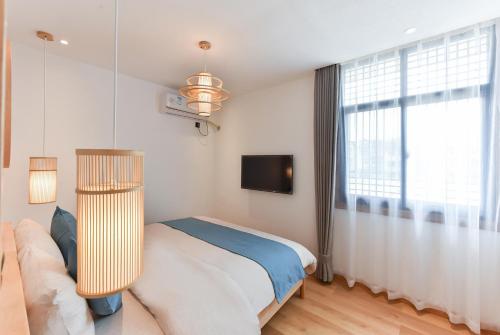 a bedroom with a bed and a couch and a tv at Yifangyan - Tingyuan Qingshe Hostel in Fenghuang