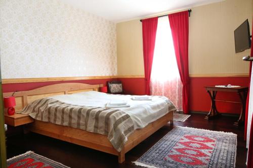 1 dormitorio con 1 cama y una ventana con cortinas rojas en Sasfészek Vendégház, en Alsótündérmajor