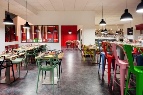 ヴィルールバンヌにあるIbis Styles Lyon Villeurbanne Parc de la Tête d'Orのカラフルなテーブルと椅子が備わるレストラン