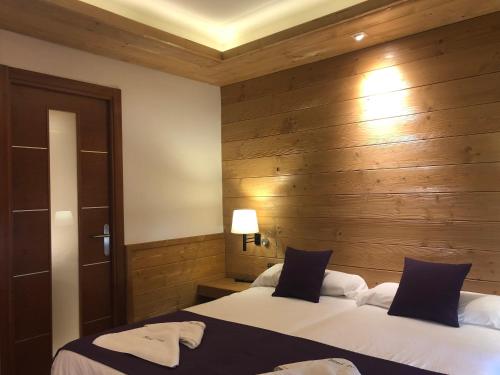 two beds in a room with wooden walls at Hostal Piteus in Sant Llorenc de Morunys