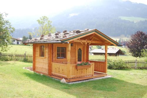 a small wooden cabin in a yard with a fence at Pension Sonnblick in Westendorf