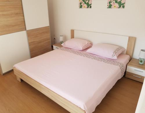 een slaapkamer met een bed met 2 roze kussens bij Apartments and Rooms Rosemari in Mali Lošinj