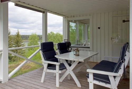 un porche con una mesa blanca y 2 sillas en Stora Timrarö Unwind, en Vadholma