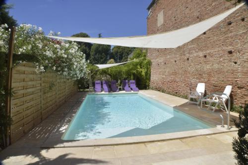 a swimming pool in a yard with a brick wall at L'Armateur in Moissac