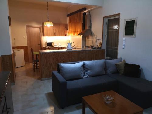 a living room with a blue couch and a kitchen at Leonidas Private Apartment in Sparta in Sparta