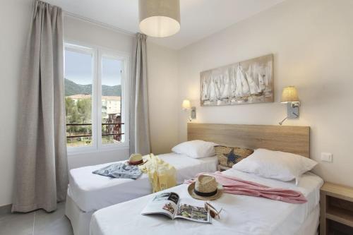 - 2 lits dans une chambre d'hôtel avec fenêtre dans l'établissement Résidence Prestige Odalys Les Canissons, à Cavalaire-sur-Mer